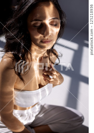 Studio fashion portrait of a charming young woman sitting with her eyes closed. 125218936