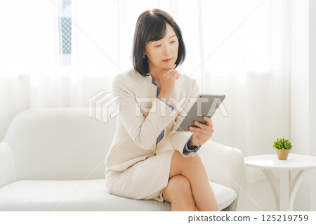 A middle-career woman talking while looking at data on a tablet 125219759