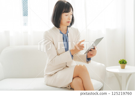 A middle-career woman talking while looking at data on a tablet A middle-career woman talking while looking at data on a tablet 125219760