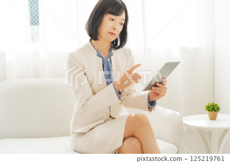 A middle-career woman talking while looking at data on a tablet A middle-career woman talking while looking at data on a tablet 125219761