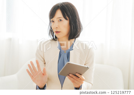 一位中年女性一邊聊天一邊查看平板電腦上的數據 一位中年女性一邊聊天一邊查看平板電腦上的數據 125219777