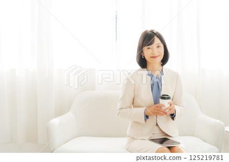 A middle-career woman taking a break with a drink 125219781