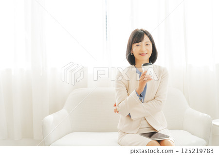 一位中年女性正在小酌一杯 一位中年女性正在小酌一杯 125219783