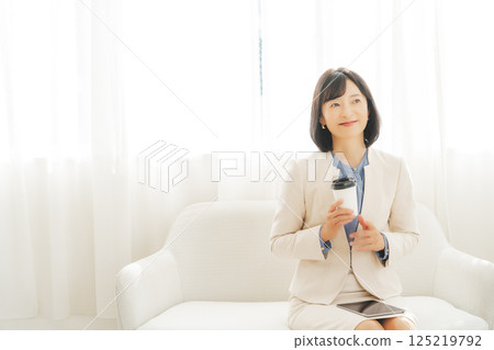 A middle-career woman taking a break with a drink 125219792