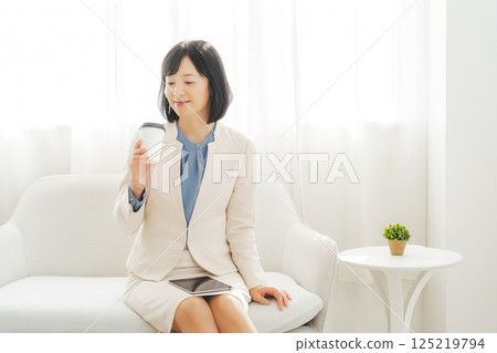 一位中年女性正在小酌一杯 125219794