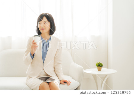 A middle-career woman taking a break with a drink 125219795