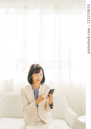 A middle-aged career woman contacting someone via smartphone A middle-aged career woman contacting someone via smartphone 125219810