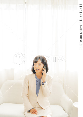 A middle-aged career woman contacting someone via smartphone A middle-aged career woman contacting someone via smartphone 125219811