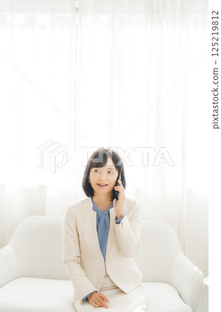 一位中年職業婦女透過智慧型手機聯繫某人 125219812