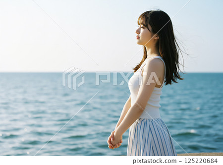 A woman standing on a windy beach 125220684