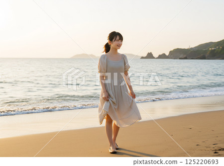 Woman walking on the sandy beach at dusk 125220693