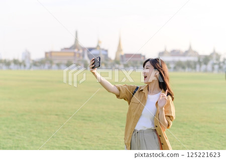 Traveler asian woman in her 30s explores the Grand Palace with a local guide. Uncover hidden gems and immerse yourself in Thai culture with her adventure. 125221623