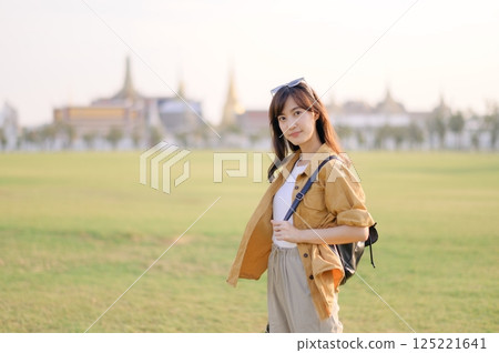 A Traveler Asian woman in her 30s exploring Wat Pra Kaew. From stunning architecture to friendly locals, she cherishes every moment, capturing it all in her heart and camera for years to come. 125221641