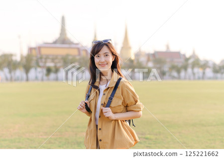 A Traveler Asian woman in her 30s exploring Wat Pra Kaew. From stunning architecture to friendly locals, she cherishes every moment, capturing it all in her heart and camera for years to come. 125221662