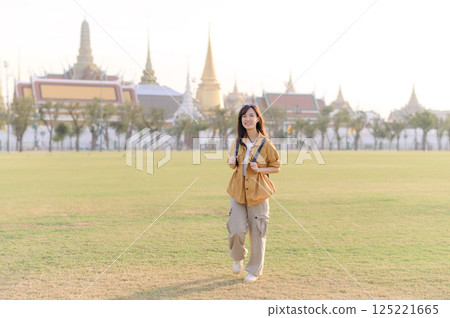 A Traveler Asian woman in her 30s exploring Wat Pra Kaew. From stunning architecture to friendly locals, she cherishes every moment, capturing it all in her heart and camera for years to come. 125221665