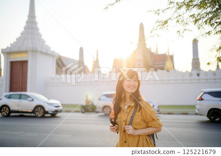 Traveler asian woman in her 30s stands bathed in the golden glow of sunset, embracing the freedom of exploration. on summer holiday weekend vacation trip in Bangkok, Thailand Traveler asian woman in her 30s stands bathed in the golden glow of sunset, embracing the freedom of exploration. on summer holiday weekend vacation trip in Bangkok, Thailand 125221679