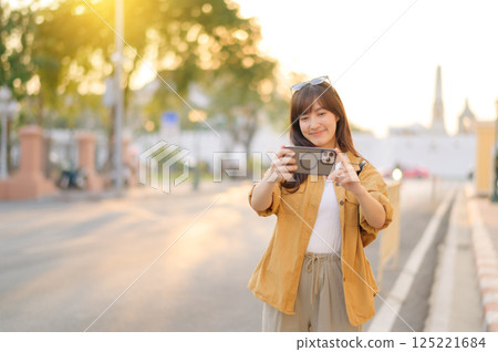 Traveler asian woman in her 30s using smartphone to take a photo while traveling urban street in Bangkok, Thailand Traveler asian woman in her 30s using smartphone to take a photo while traveling urban street in Bangkok, Thailand 125221684