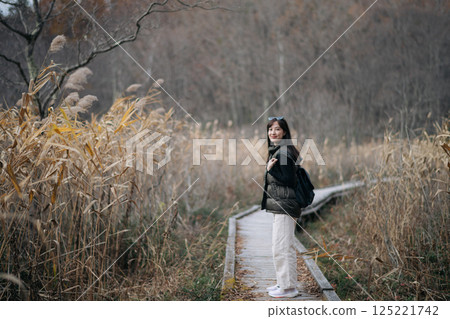 A lone Asian woman enjoying the vibrant fall foliage on a hiking trail in Japan, relishing the freedom of a solo adventure. A lone Asian woman enjoying the vibrant fall foliage on a hiking trail in Japan, relishing the freedom of a solo adventure. 125221742