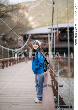 Achievement and happiness, Asian woman in a blue jacket explores nature's beauty. A stylish traveler in Japan, standing by a lake, reflecting on a journey of excitement. Achievement and happiness, Asian woman in a blue jacket explores nature's beauty. A stylish traveler in Japan, standing by a lake, reflecting on a journey of excitement. 125221746