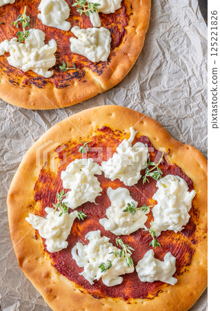 Mini pizzas baked with tomato sauce, stracciatella cheese, and fresh thyme garnish Mini pizzas baked with tomato sauce, stracciatella cheese, and fresh thyme garnish 125221826