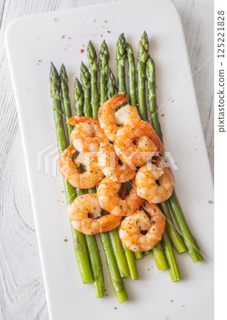 Crisp fried shrimp rest atop tender asparagus on a bright white plate 125221828
