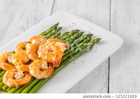 Crisp fried shrimp rest atop tender asparagus on a bright white plate Crisp fried shrimp rest atop tender asparagus on a bright white plate 125221829