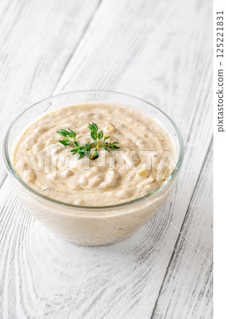 Creamy blue cheese sauce garnished with thyme in clear bowl on table 125221831