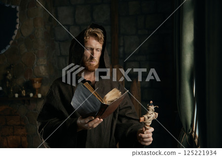 Thoughtful medieval monk reading ancient book in cathedral Thoughtful medieval monk reading ancient book in cathedral 125221934