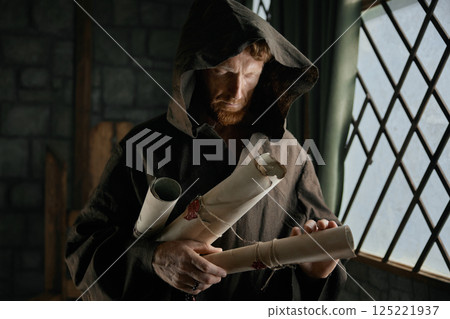 Medieval monk holding obsolete historical parchments and holy manuscripts Medieval monk holding obsolete historical parchments and holy manuscripts 125221937