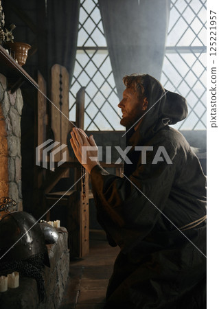 Solitary desperate priest kneeling before church altar in mystical smoke 125221957