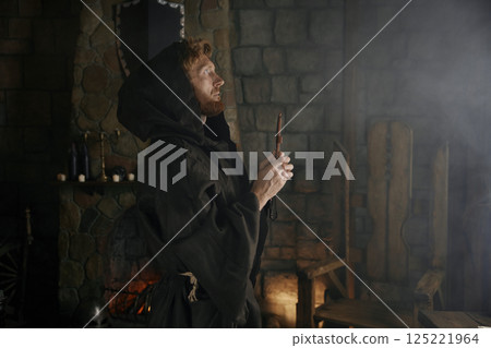 Faithful priest in robe hood praying with rosary beads and cross Faithful priest in robe hood praying with rosary beads and cross 125221964