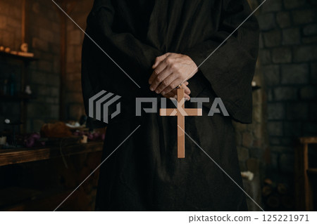 Closeup view cropped shot with golden cross in priest monk hands Closeup view cropped shot with golden cross in priest monk hands 125221971