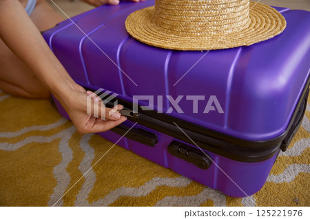 Cropped shot of unrecognizable woman zipping travel suitcase luggage 125221976