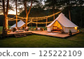 Elegant glamping setup with string lights in serene forest 125222109