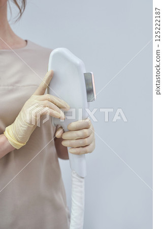 Female adult holding laser hair removal device with gloves in clinical setting 125222187