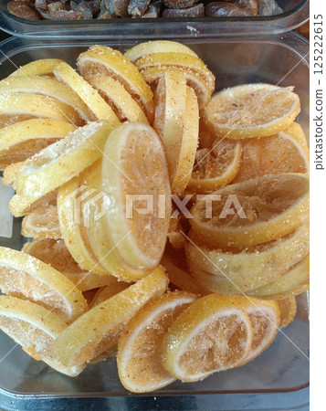 A Sweet and tangy candied lemon slices arranged beautifully in clear container, showcasing their vibrant yellow color and sugary coating A Sweet and tangy candied lemon slices arranged beautifully in clear container, showcasing their vibrant yellow color and sugary coating 125222615