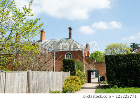 A historic building with a red brick chimney and a narrow street under bright sunlight in Hatchlands, a suburb of London 125222771