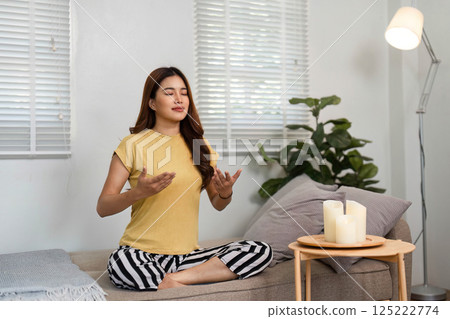 Self-Care and Serenity. A woman creates a calming atmosphere with candles during her meditation. Self-Care and Serenity. A woman creates a calming atmosphere with candles during her meditation. 125222774