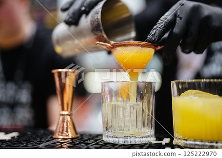 Crafting a refreshing cocktail at a lively bar during a summer evening 125222970