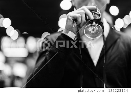 Evening gathering features a man savoring red wine in a lively atmosphere 125223124