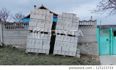 Stacked Building Blocks Neatly Arranged Against a Fence in a Backyard Environment Stacked Building Blocks Neatly Arranged Against a Fence in a Backyard Environment 125223724