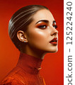 Artistic portrait of a woman in vibrant orange makeup and outfit 125224240