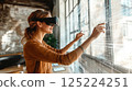 Woman using virtual reality goggles interacting with digital interface in modern space 125224251