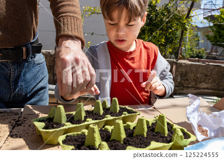 Child Planting Seeds in Recycled Egg Cartons with Adult. Eco Gardening 125224555