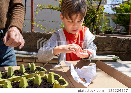 Child holding seeds ready to plant with adult guidance in eco gardening 125224557