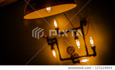 Elegant Industrial Light Fixture with Vintage-Style Bulbs Illuminating a Dark Wall, Showcasing Unique Design and Warm Atmosphere Perfect for Modern Interior Decor Elegant Industrial Light Fixture with Vintage-Style Bulbs Illuminating a Dark Wall, Showcasing Unique Design and Warm Atmosphere Perfect for Modern Interior Decor 125224693