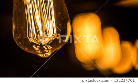 Captivating Close-Up of an Illuminated Edison Bulb with Glowing Filaments Against a Softly Blurred Background, Creating a Warm and Inviting Atmosphere in Stylish Lighting Design 125224701