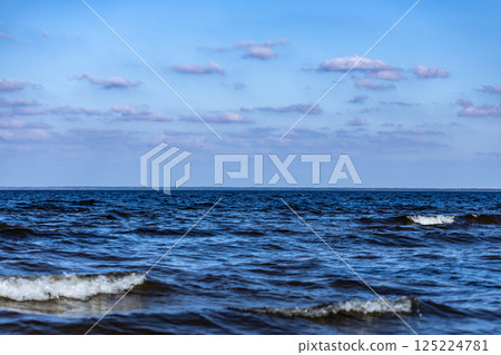 A Serene Seascape: Waves Gently Lapping Against the Shore Under a Clear Blue Sky with Fluffy Clouds, Perfect for Relaxation and Contemplation in Nature's Embrace A Serene Seascape: Waves Gently Lapping Against the Shore Under a Clear Blue Sky with Fluffy Clouds, Perfect for Relaxation and Contemplation in Nature's Embrace 125224781