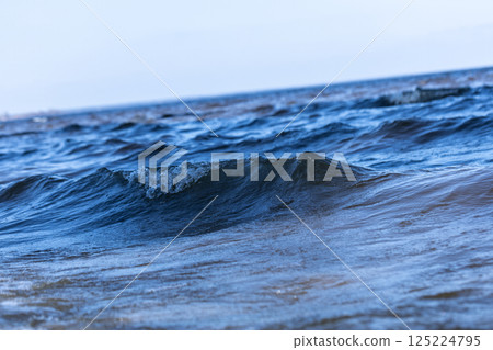 A Serene View of Gentle Ocean Waves Gliding Across the Surface Under a Clear Sky, Capturing the Beauty and Tranquility of the Seaside and Nature's Waterscape 125224795