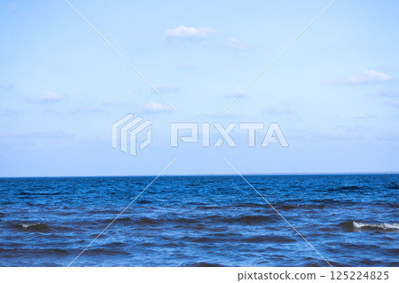 A Tranquil Seascape Featuring Vibrant Blue Waters Under a Clear Sky with Gentle Waves and Floating Clouds, Capturing the Essence of Serene Natural Beauty and Coastal Charm A Tranquil Seascape Featuring Vibrant Blue Waters Under a Clear Sky with Gentle Waves and Floating Clouds, Capturing the Essence of Serene Natural Beauty and Coastal Charm 125224825